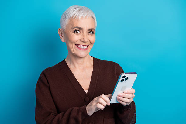 istock Charming mature woman using smartphone against blue backdrop and smiling 2233295150
