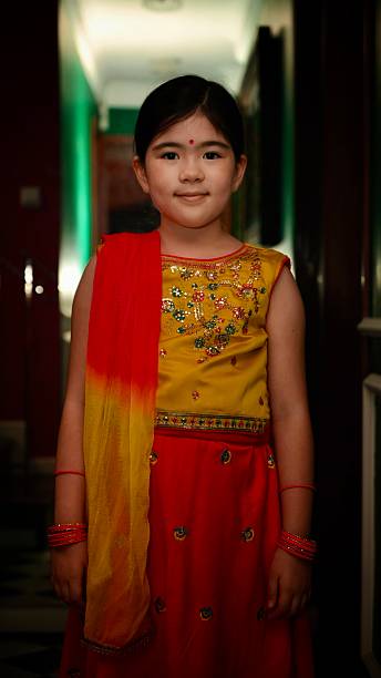 Small baby girl celebrating Diwali festival at home against light background. Diwali is the Hindu festival of lights with its variations also celebrated in other Indian religions. It symbolises the spiritual \