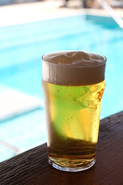istock Refreshing beer overflowing with foam by the pool 2233296450