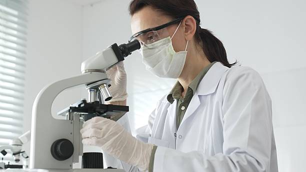 istock Female scientist in a lab coat and protective glasses examining samples through a microscope in a research laboratory. Medicine, healthcare and science concept 2233297942