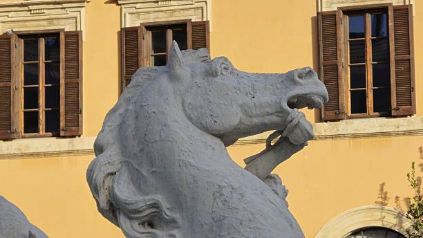Rome, Italy - 10 January 2025. A horse sculpture in the Fontana del Nettuno at Piazza Navona wrestles with a tentacled beast near sunlit Roman architecture.