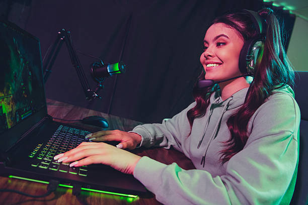 istock Enthusiastic woman gaming at home with a headset and microphone, streaming during a cyber-themed evening indoor setting 2233298698