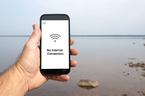 istock Hand holding smartphone displaying no internet connection by the lake 2233299176
