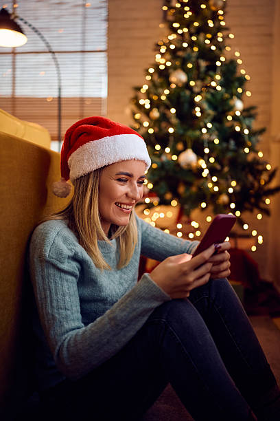 istock Happy woman using cell phone while sending greetings for Christmas holidays. 2233300881