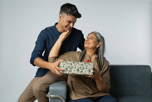 istock Family with gift box sitting on sofa against white background 2233303703