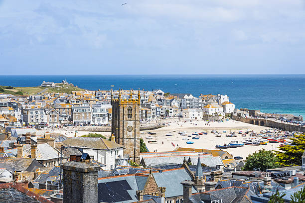 View towards the harbour at St Ives Cornwall, UK.  Boats an be seen in the harbour and people can be seen on the promenade.