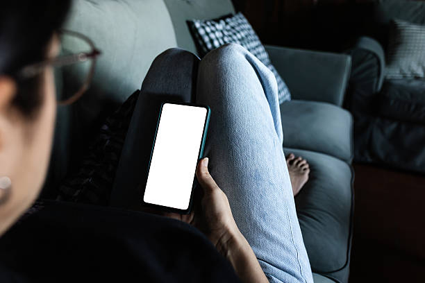 istock Unrecognizable woman relaxing on sofa holding smartphone with blank screen, ideal for mockup 2233304877