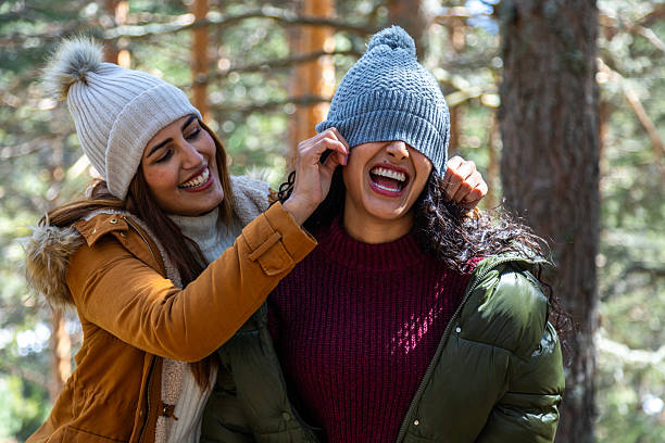 Portrait of happy young woman in sweater knitted hat celebrating winter holidays. Cheerful female showing joy victory gesture, yes sign, on white isolated background. Winter Christmas season