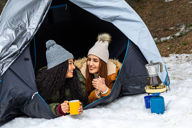 istock Two smiling women camping and drinking hot drinks in winter 2233306012