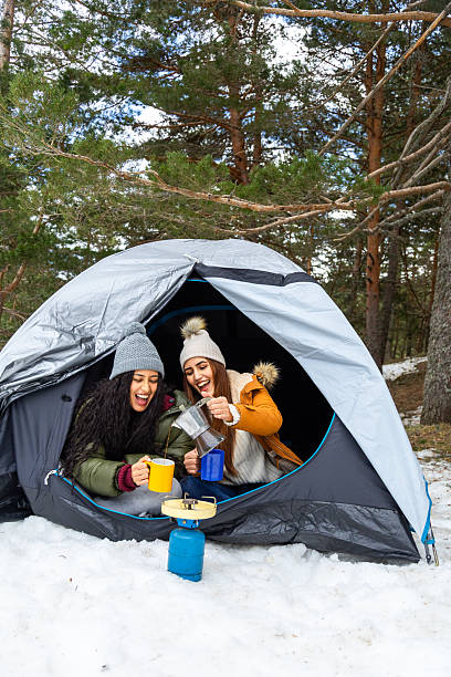 istock Two happy women drinking coffee inside tent during winter camping 2233306031