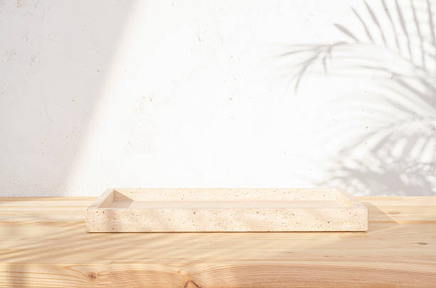 istock Empty stone tray on wooden table in dappled sunlight from window with palm leaves shade as background 2233306775