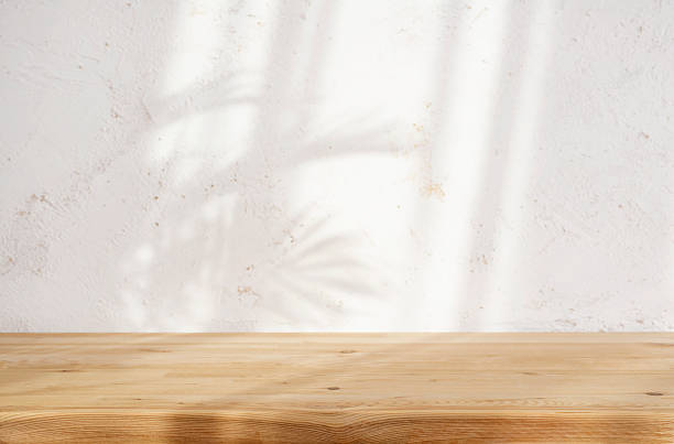 istock Blurred palm foliage shadow on light abstract plaster wall background with wooden table for presentation 2233306783