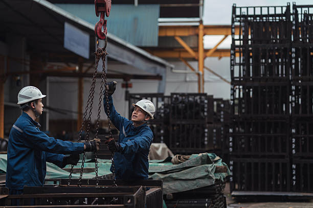 istock Asian blue collar coworkers rigging up chains to a pulley system for heavy lifting 2233306932