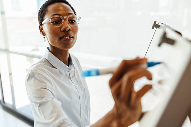 istock Professional woman writing on a whiteboard in a modern office setting 2233308838
