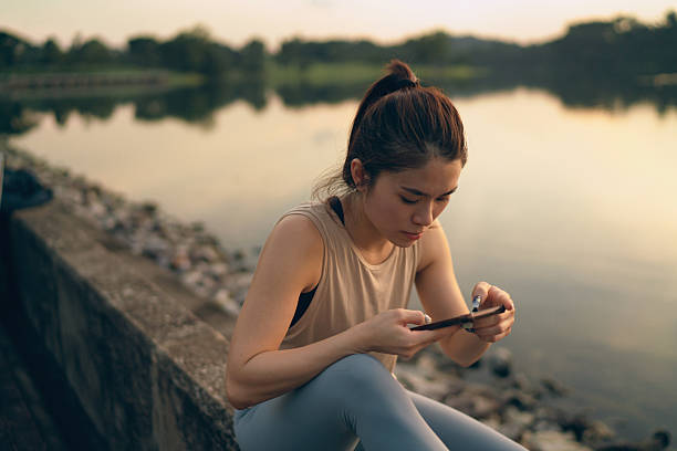 istock Asian woman relaxing and checking her phone after a workout 2233311035