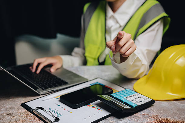 istock Professional Construction Worker in Safety Vest Using Laptop and Calculator for Project Management and Planning 2233320572