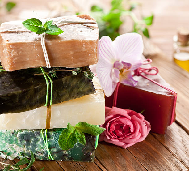 istock Handmade natural soaps tied with rustic strings on wooden table. Fresh green leaves and blooming flowers are near about. 2233321483