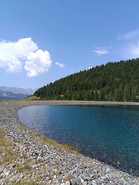 istock Lake in the mountains white clouds forest beauty 2233323708