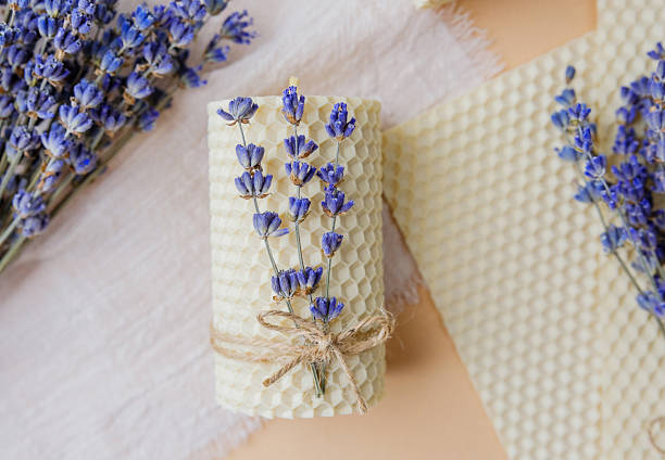 Handmade beeswax candle decorated with lavender on pastel background