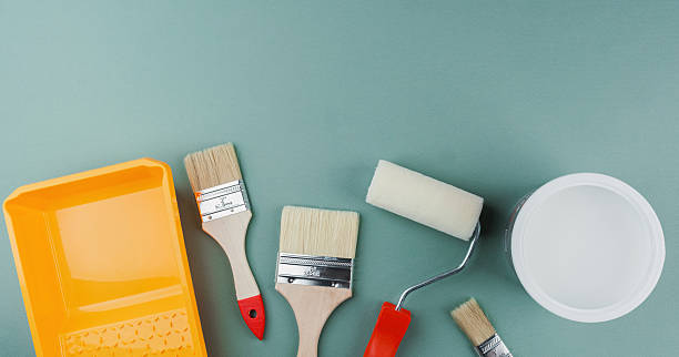istock Scattered paint tools with roller, brushes, tray and bucket on green background for interior renovation and DIY project concept 2233324423