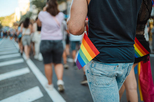 istock Young man walking at gay pride parade with rainbow flag 2233325166