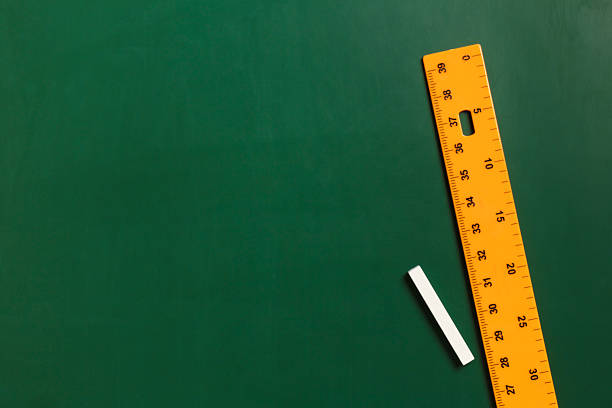 istock Ruler and chalk on green chalkboard, top view. Space for text 2233327042