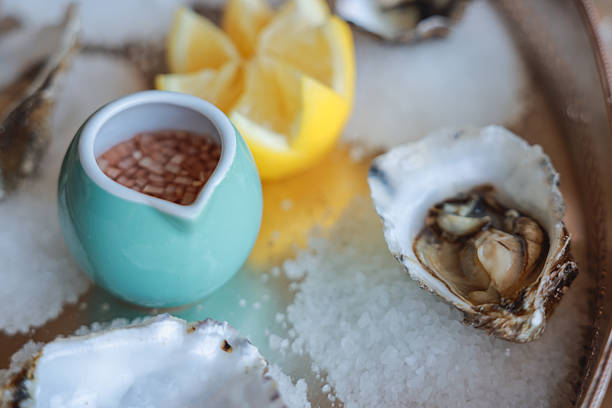 Oysters with lemon served on silver round platter. Luxury delicatessen seafood