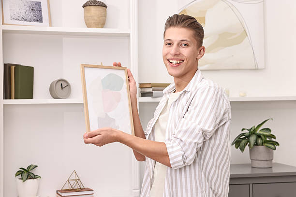 istock Smiling decorator with abstract picture near shelving unit indoors 2233329044