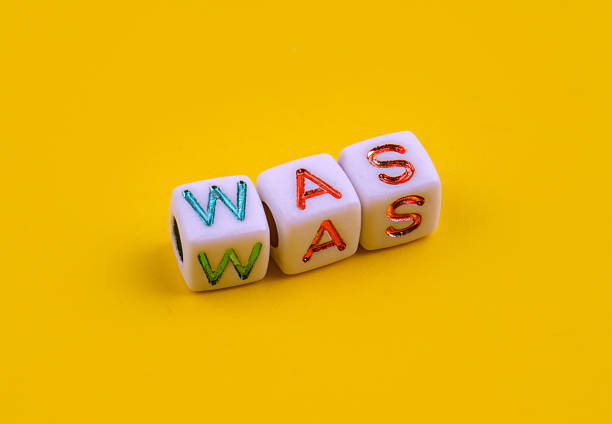 istock Three white dice with colorful engraved letters spelling the word WAS placed on a bright yellow background. 2233329465