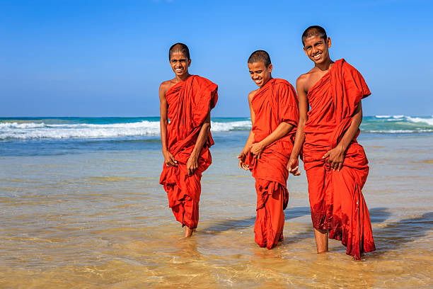 Three Sri Lankan young buddhist monks walking on the beach near Galle, Sri Lanka