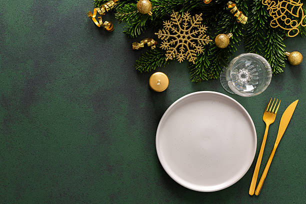 istock A Christmas table setting with an empty plate and cutlery on a green background. Spruse branches and golden tree decorations add elegance and festive cheer to the scene 2233338245