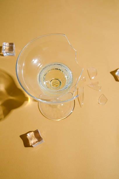 istock Broken clear glass cup with liquid and ice cubes on a neutral background with light shadows. 2233340778