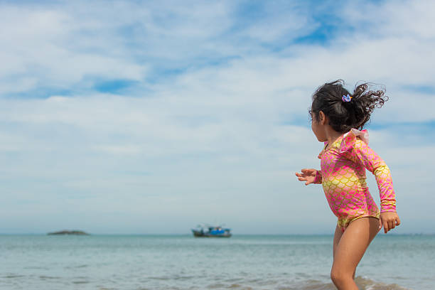 Little girl raises a kite in a sky where some other kites are also flying