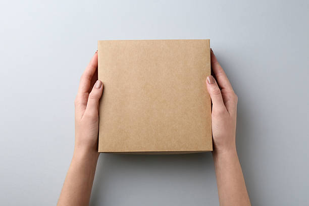istock Woman with blank cardboard box on white background, top view. Mockup for design 2233344331