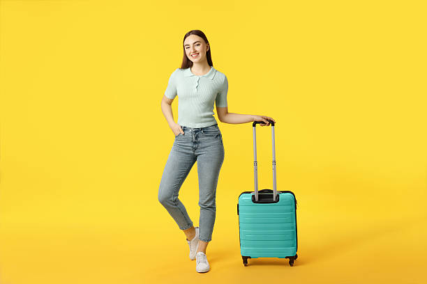 istock Young woman with suitcase on orange background 2233344909