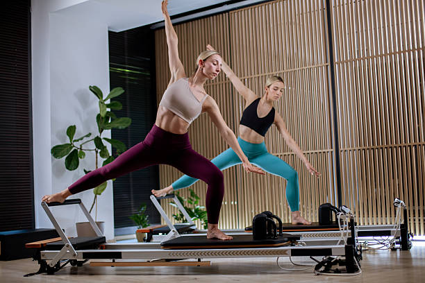 istock Workout session featuring two women practicing reformer pilates in a modern studio with natural light and wooden accents 2233347257