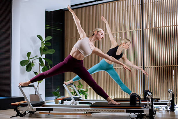 istock Professional workout session using reformer pilates machines in a bright studio with large windows and wooden decor in the morning 2233347931