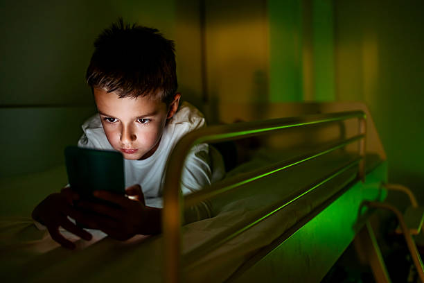 istock Young Boy Lying In Bed at Night Using Smartphone 2233351018