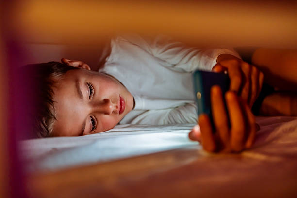 istock Young Child Using a Smartphone in Bed at Night 2233351093
