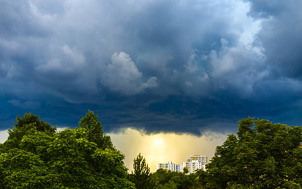 istock Ominous thunderclouds over landscape with trees and city buildings 2233351523