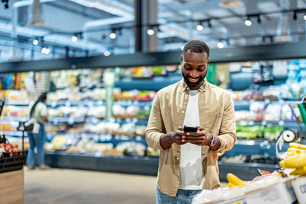 istock Man Using Smartphone While Shopping in a Grocery Store for Fresh Produce 2233353121
