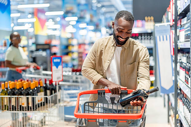 istock Smiling Man Shopping for Wine in a Modern Supermarket 2233353309