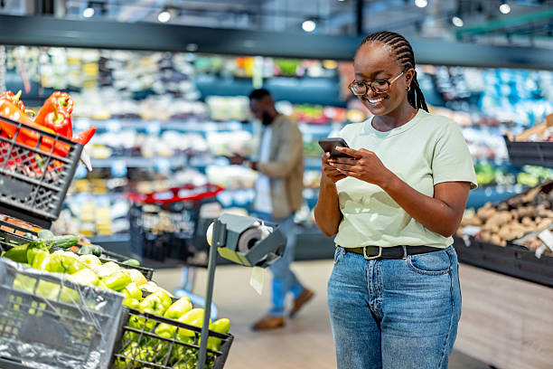 istock Smiling Woman Using Smartphone While Shopping in a Grocery Store 2233353315