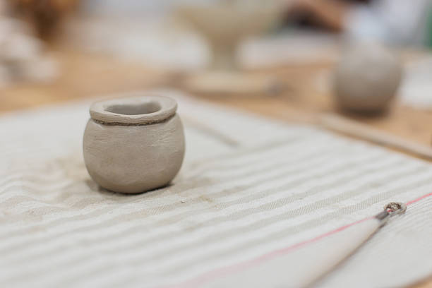 Small pottery jar crafted from clay, photographed in detail as part of a pottery class in an art studio.