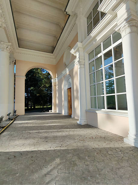 istock A neoclassical colonnade with tall white pillars, large windows, and textured flooring under a vaulted ceiling. The play of natural light enhances the grandeur of the design. 2233362734