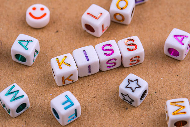 istock Letter beads spelling KISS are centrally arranged on a textured surface. 2233362961