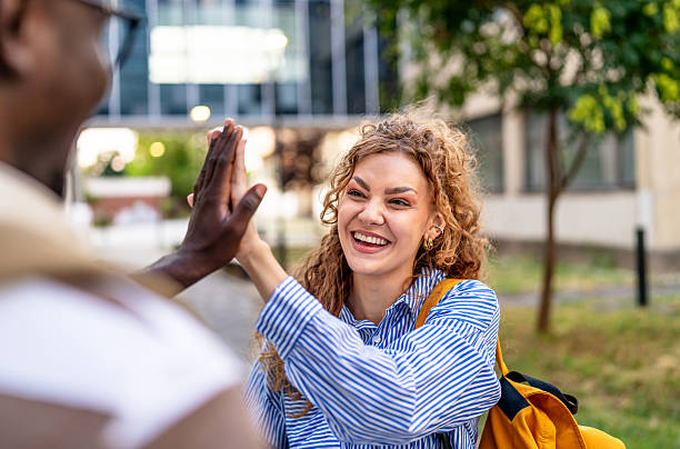 istock Happy students giving high five outdoors 2233363020