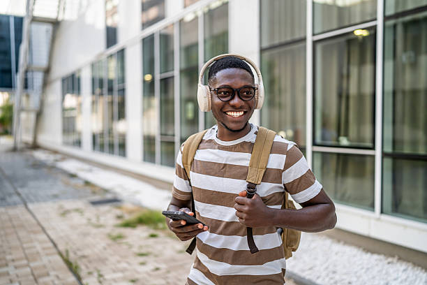 istock Smiling student listening to music while walking outdoors 2233363394