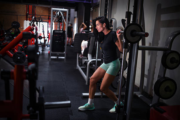 Young Woman Doing Squats on Smith Machine at Gym