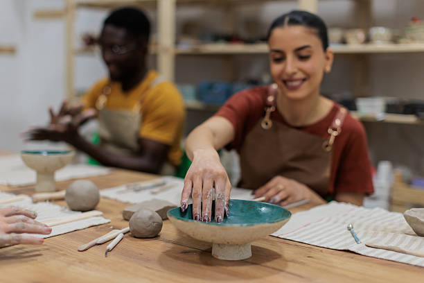 istock Woman wetting fingers while sculpting clay 2233365616